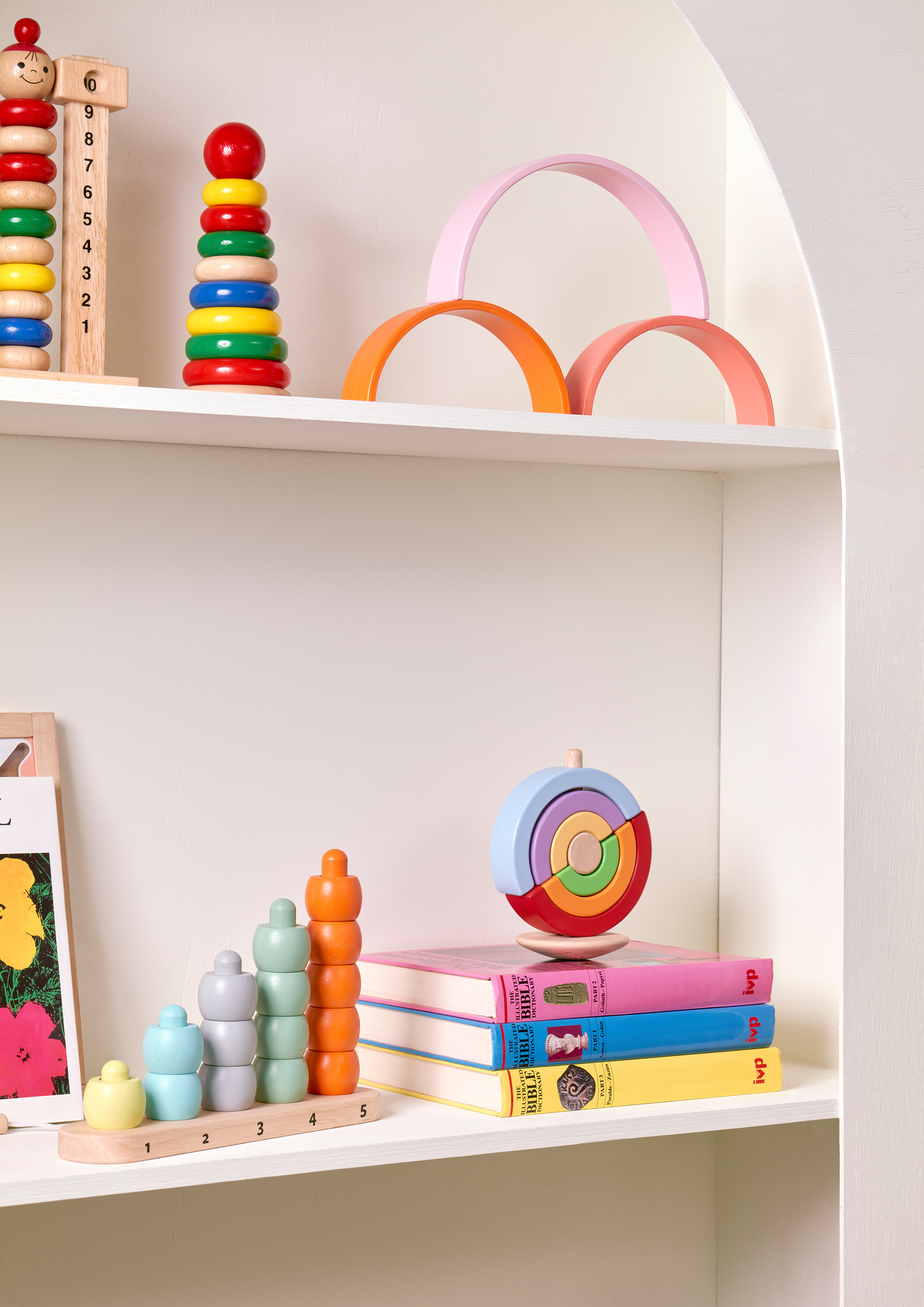 Wooden stacking toy with graduated half-circle pieces to place on a rod. Encourages recognition of size and balance, fine motor skill development, and turn-taking play.