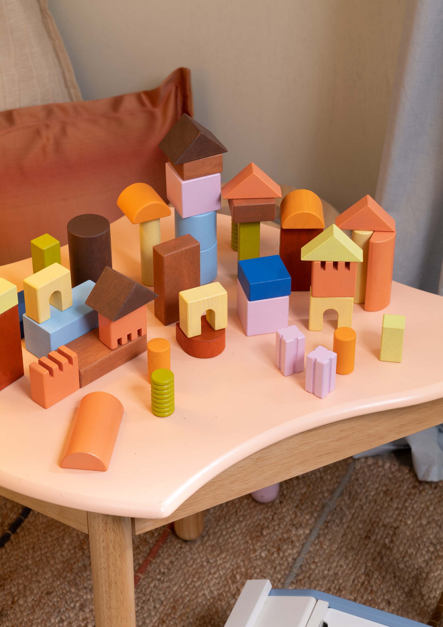 A variety of wooden blocks in different shapes including cubes and cylinders, arranged to form a larger cube-shaped structure.