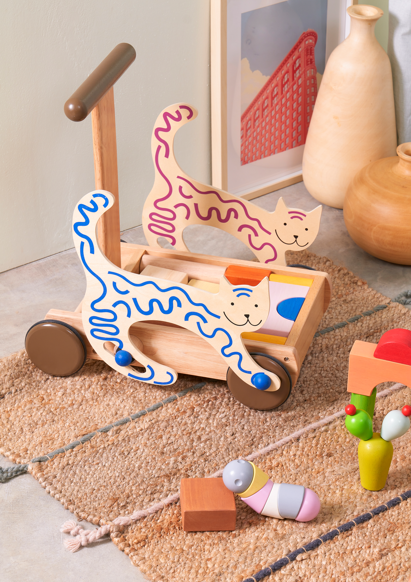 A colorful caterpillar-shaped rattle with segments in pastel pink, yellow, and blue colors, with a soft, plush texture.