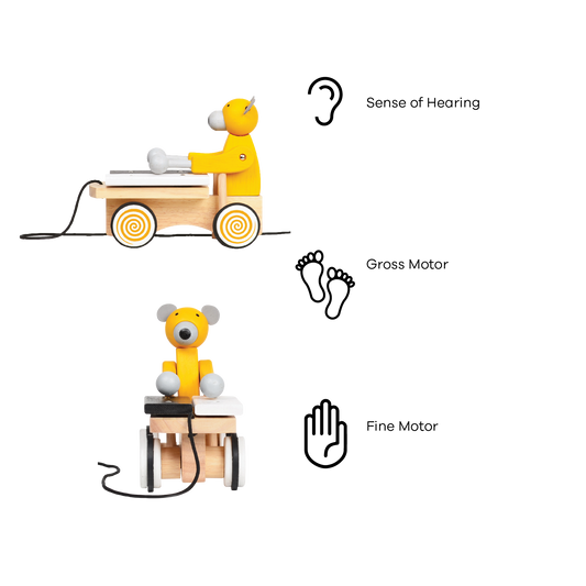 A colorful toy xylophone in the shape of a cartoon bear with yellow body and black hair, attached to a wooden structure resembling a stomach and intestines, on a spiral-patterned base.