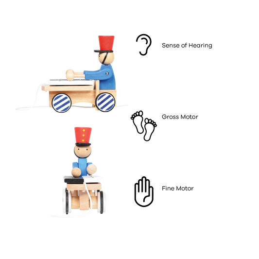 A wooden pull-along toy featuring a character resembling Pinocchio with a red hat, red jacket, attached to a small wooden xylophone on wheels with a red and white zig-zag pattern.