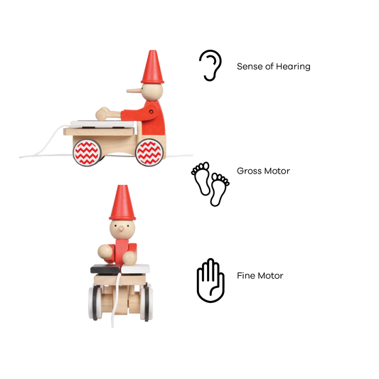 A wooden pull-along toy featuring a character resembling Pinocchio with a red hat, red jacket,  attached to a small wooden xylophone on wheels with a red and white zig-zag pattern.