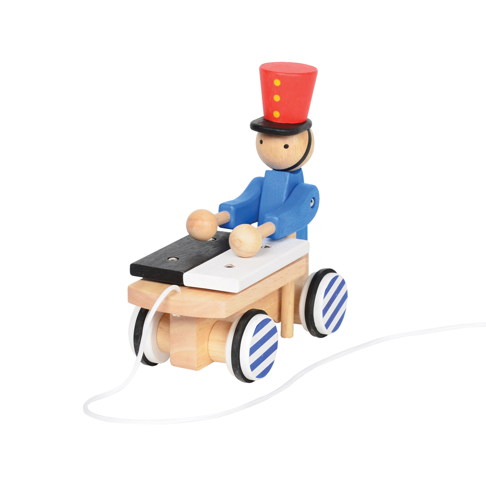 A wooden pull-along toy featuring a character resembling Pinocchio with a red hat, red jacket, attached to a small wooden xylophone on wheels with a red and white zig-zag pattern.